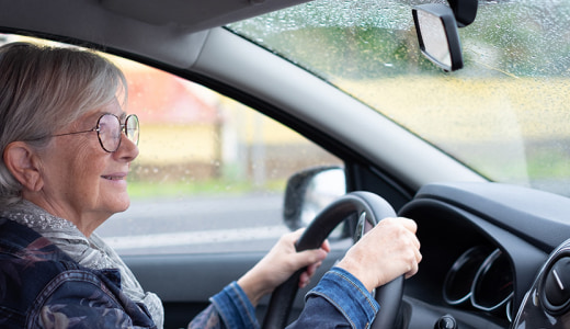 雨の中、運転するシニア女性